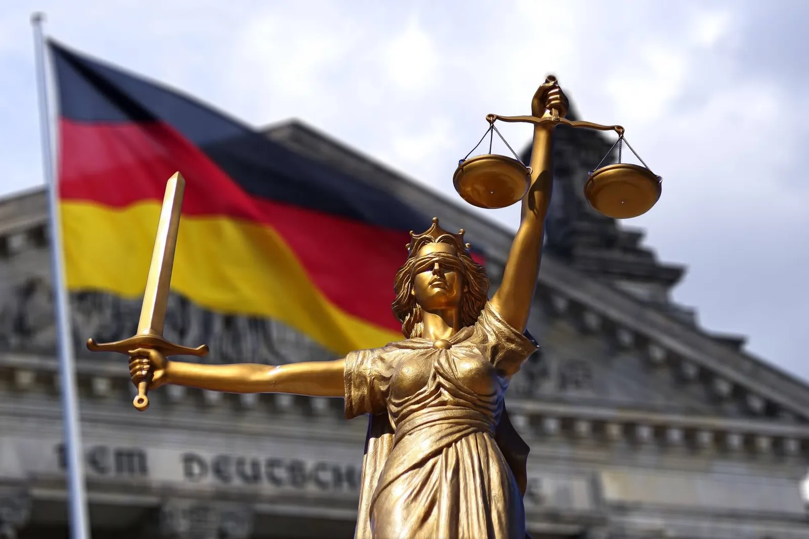 Statue of Lady Justice against the German flag and the Reichstag building in the context of legal liability for impressum errors on a website